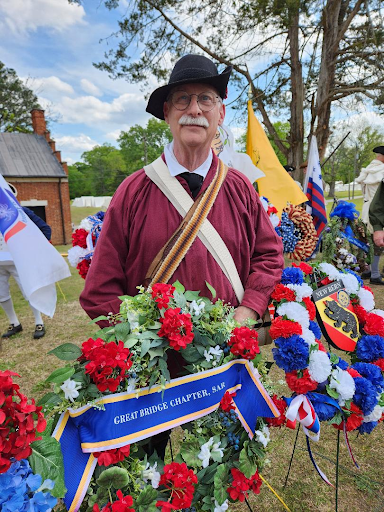 Great Bridge chapter president Stuart Whitehead in colonial attire standing with chapter wreath.