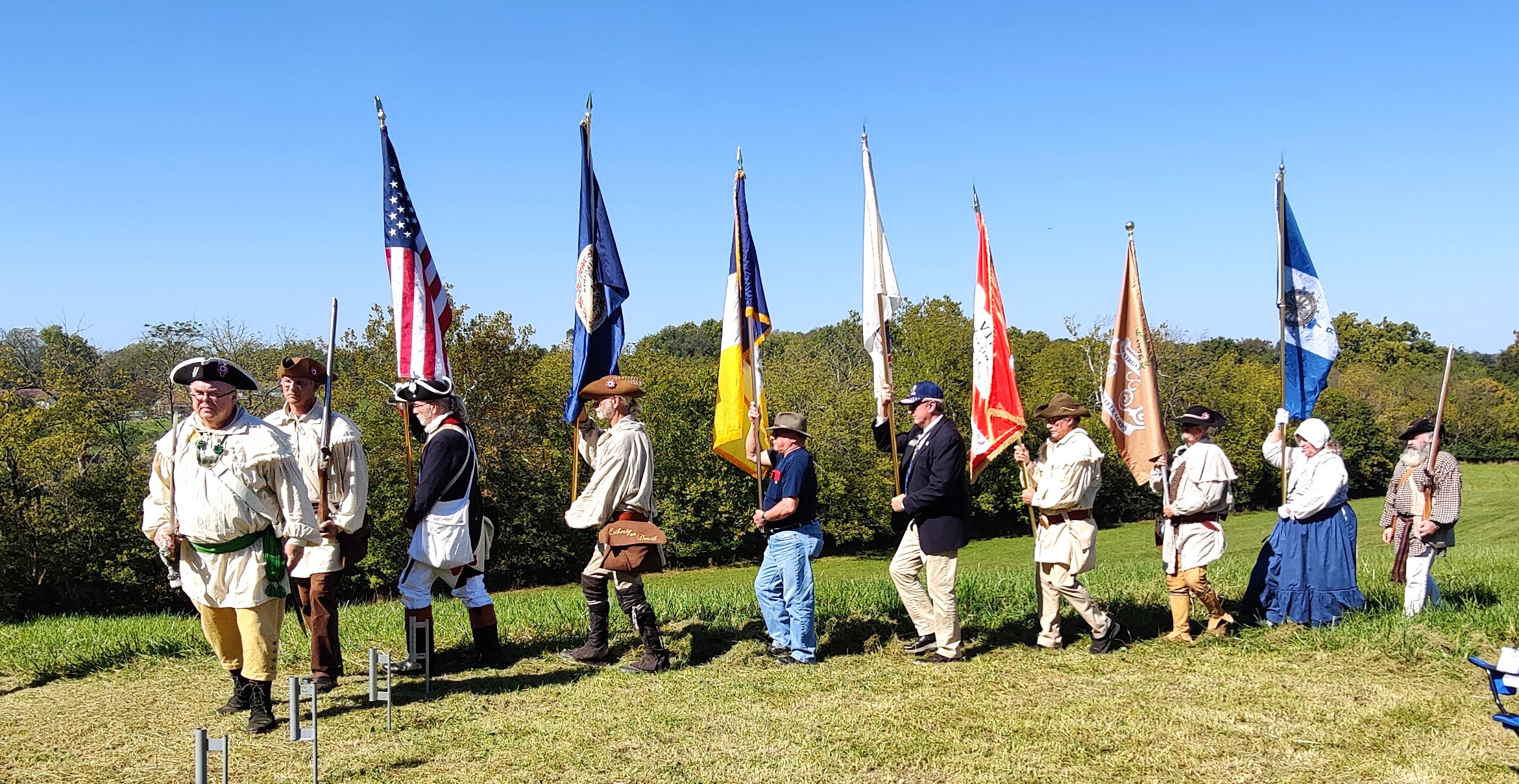 Color guard marching to render honors at grave marking ceremony.