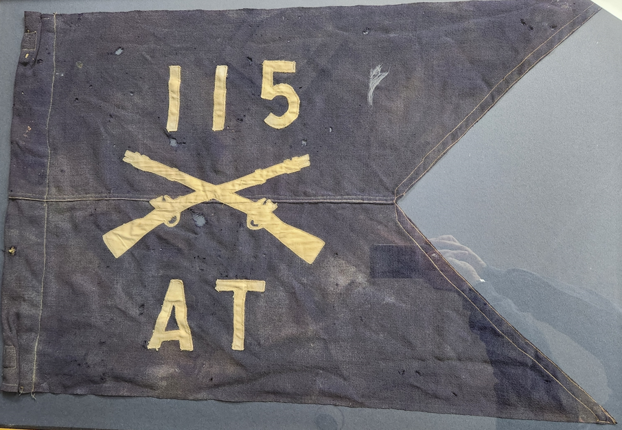 Guidon of the 115th Maryland National Guard Regiment. The guidon is dark blue with a swallowtail design. It features the number 